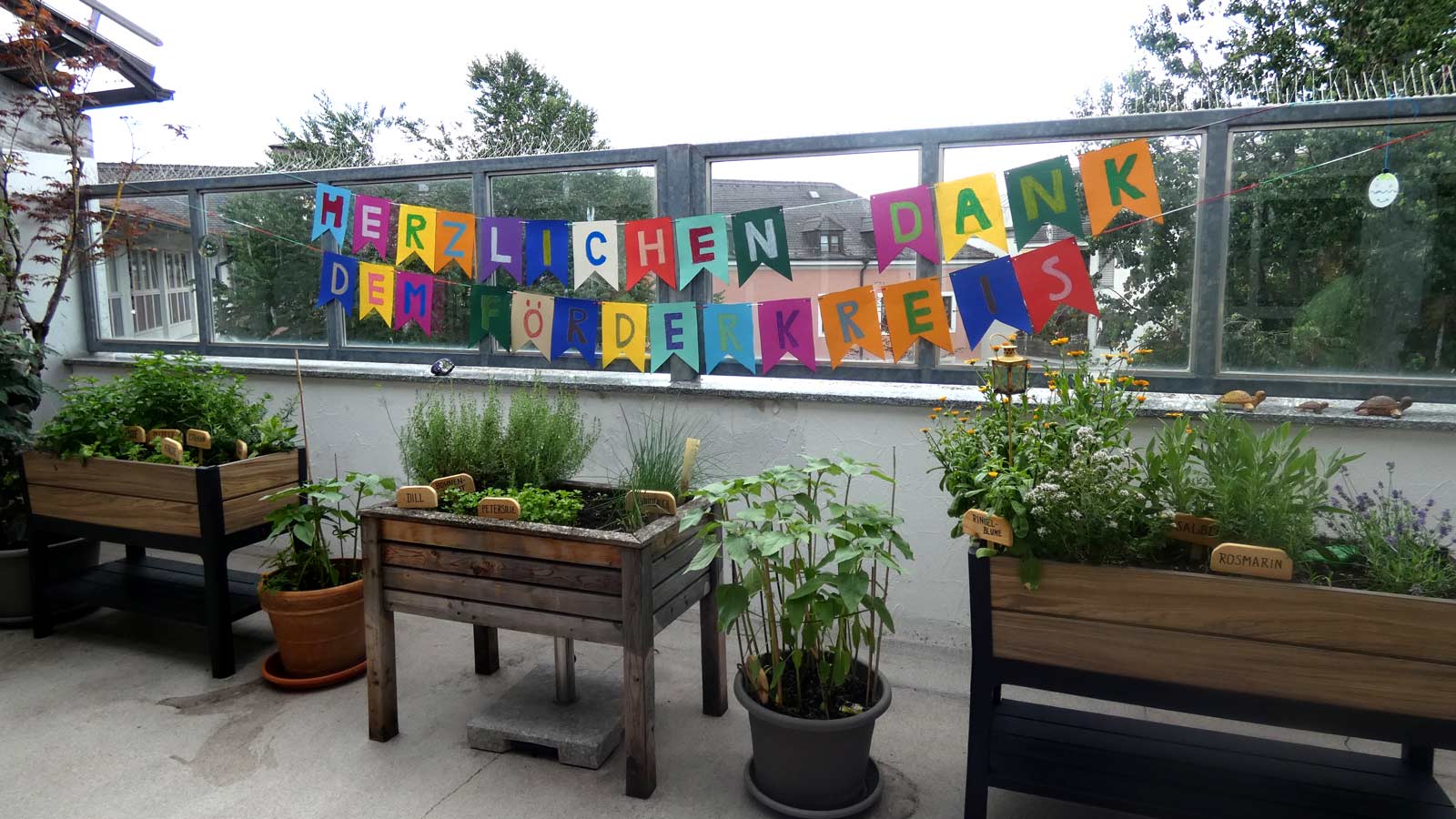 Ein Schriftband mit "Herzlichen Dank dem Förderkreis" darunter Blumenkästen